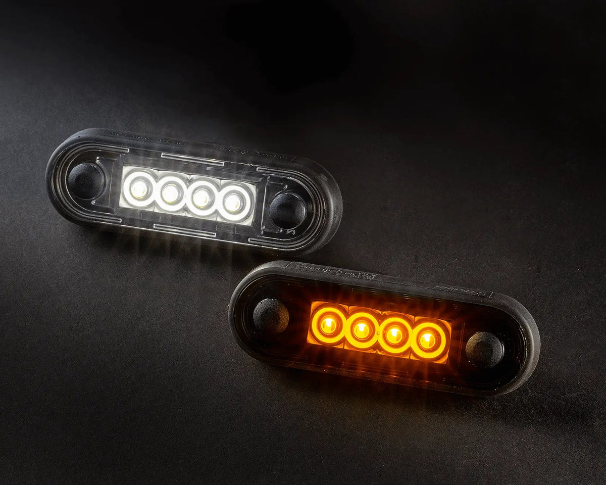 Oval LED marker lights, one white and one amber, on a black surface