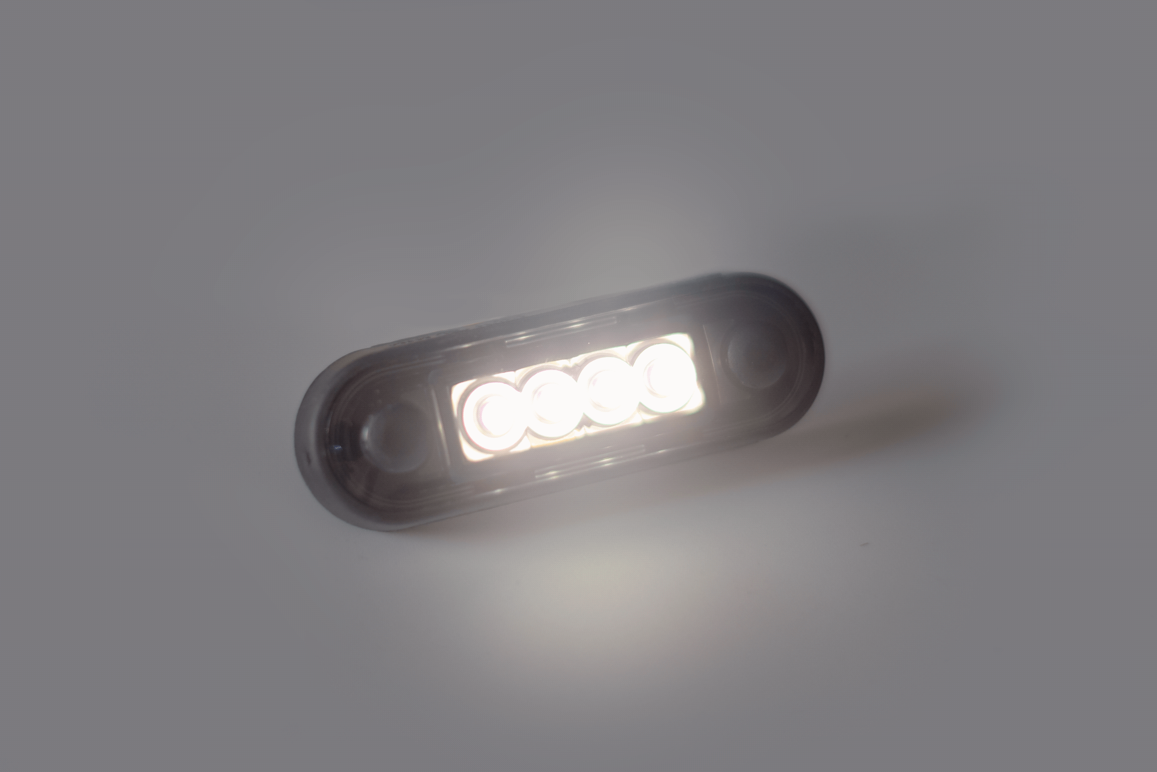 LED oval marker light glowing on a plain gray background